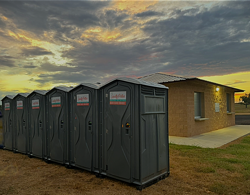 Port-a-potties in front of a building with a sunset
